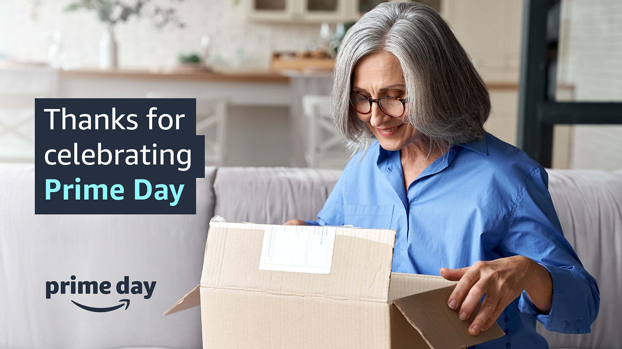An image of a woman smiling while opening a package. Text on the image reads "Thanks for celebrating Prime Day" and there is the Amazon smile logo with the words "Prime Day" above it lower down. 