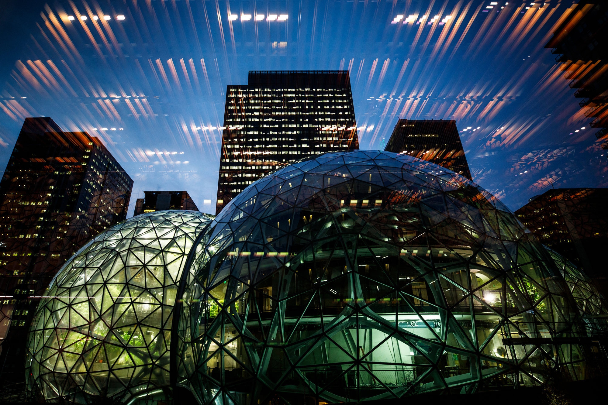 Amazon Spheres lit up at night, with lighting reflection in the glass. 