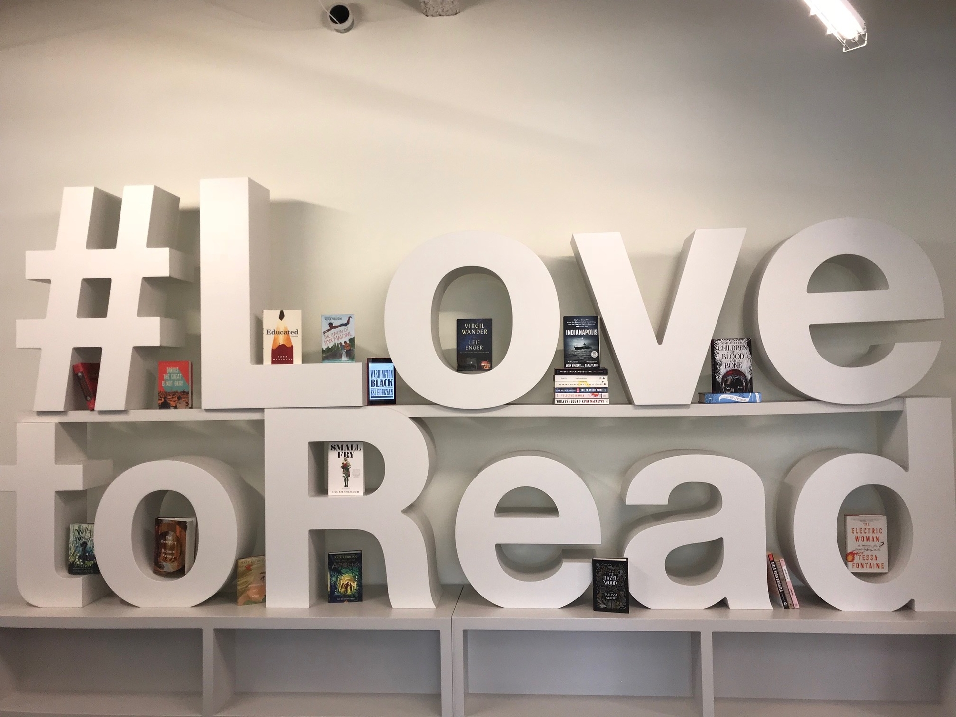 Large letters on a bookshelf spell out #LovetoRead. Between letters are some of the top books of the year. 