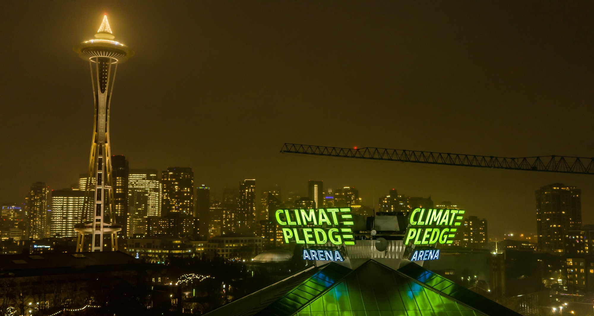 The Climate Pledge Arena signage lit up, with Seattle's Space Needle and skyline showing behind it.