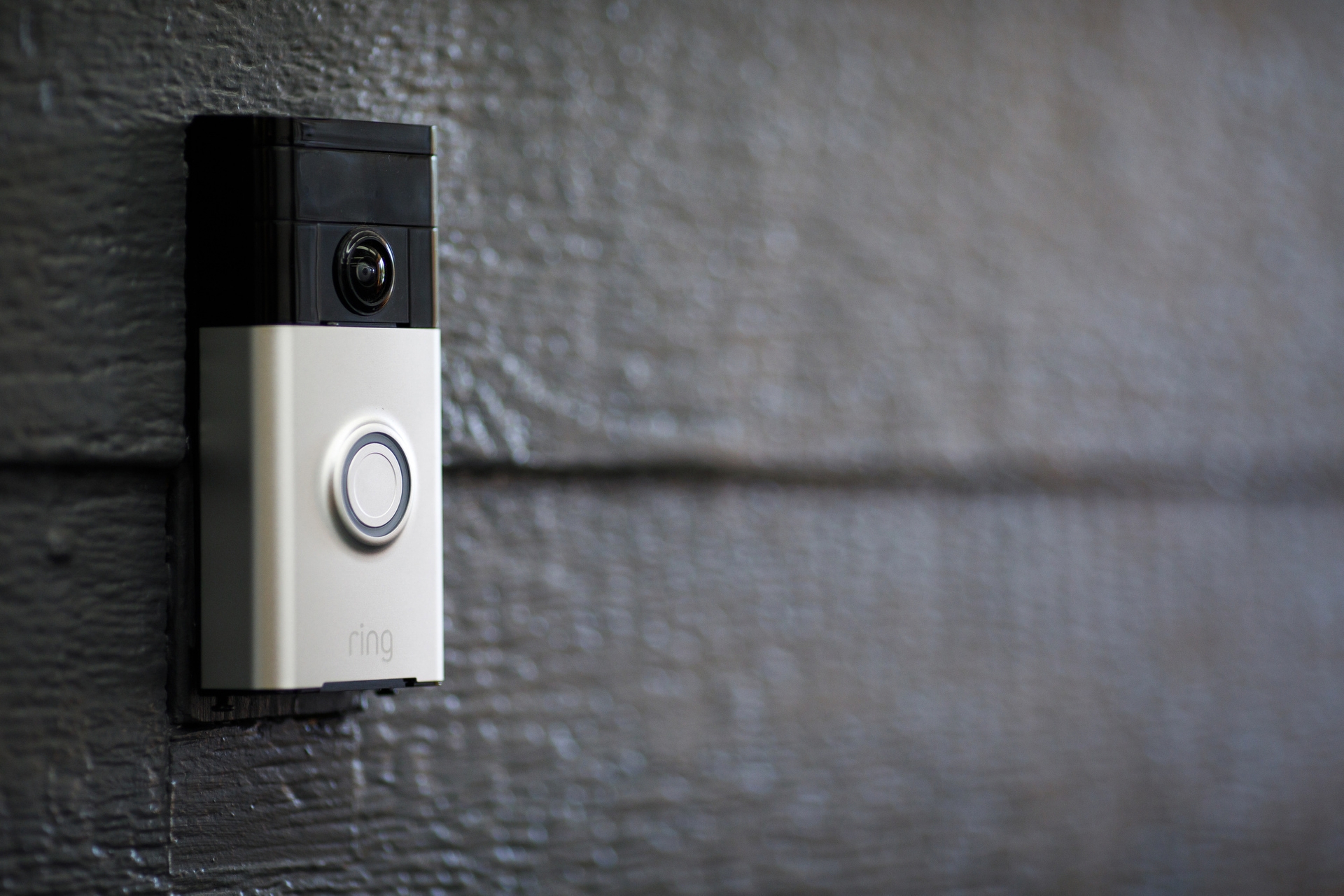 A Ring video doorbell on a black wall.
