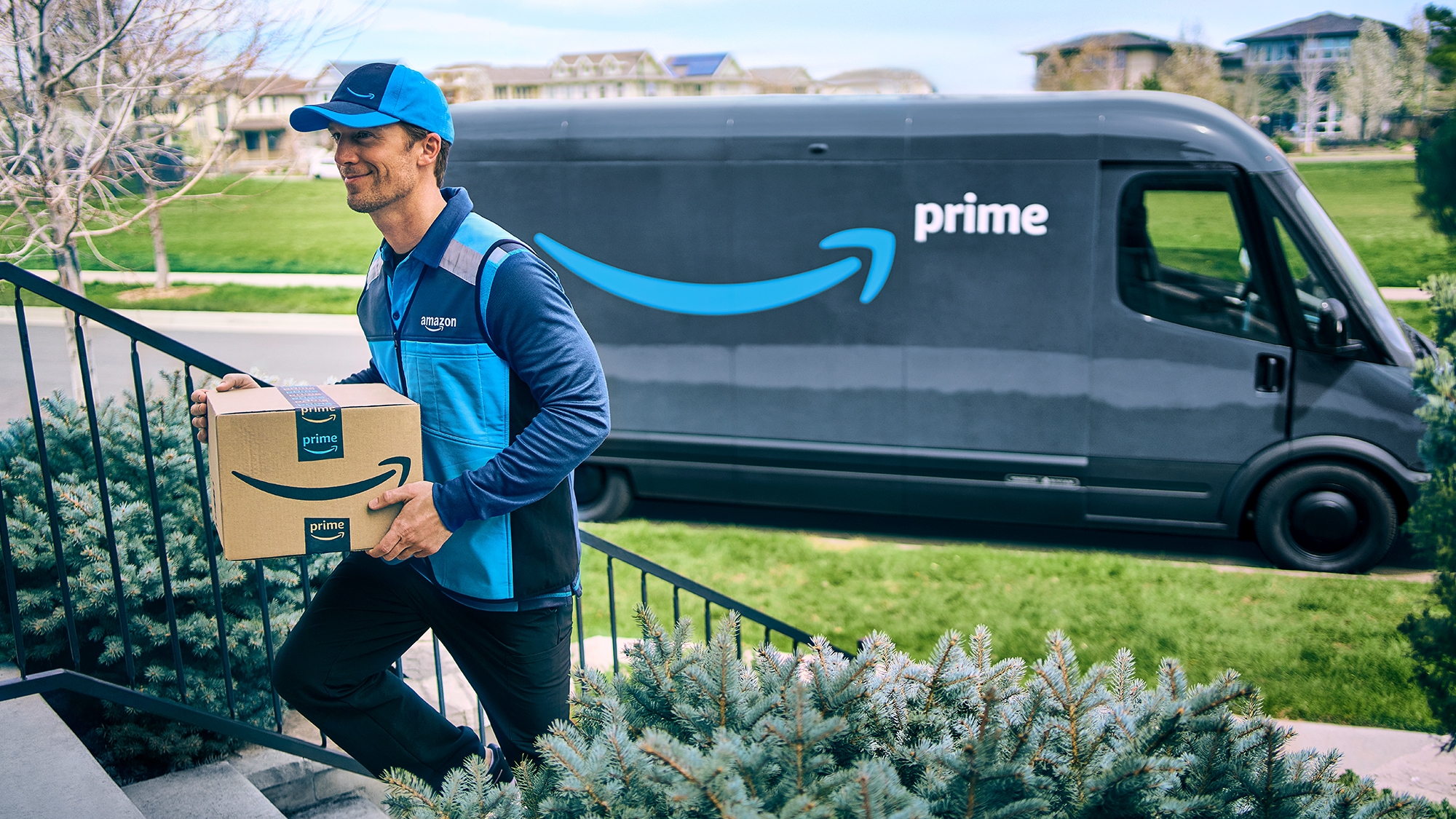 Amazon Prime delivery driver walks up the steps to deliver a package with his Prime delivery van in the background.