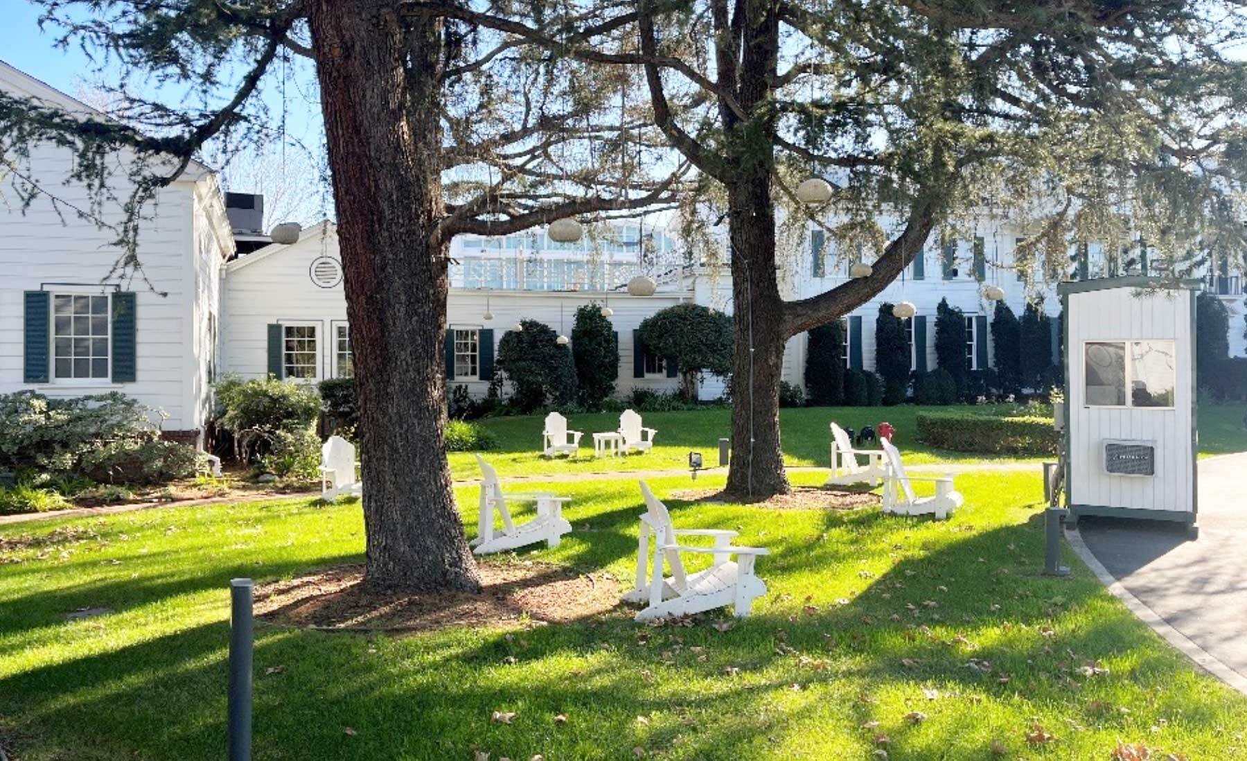 An image of a large grass yard with white chairs in the lawn. The Culver Studios mansion is in the background.
