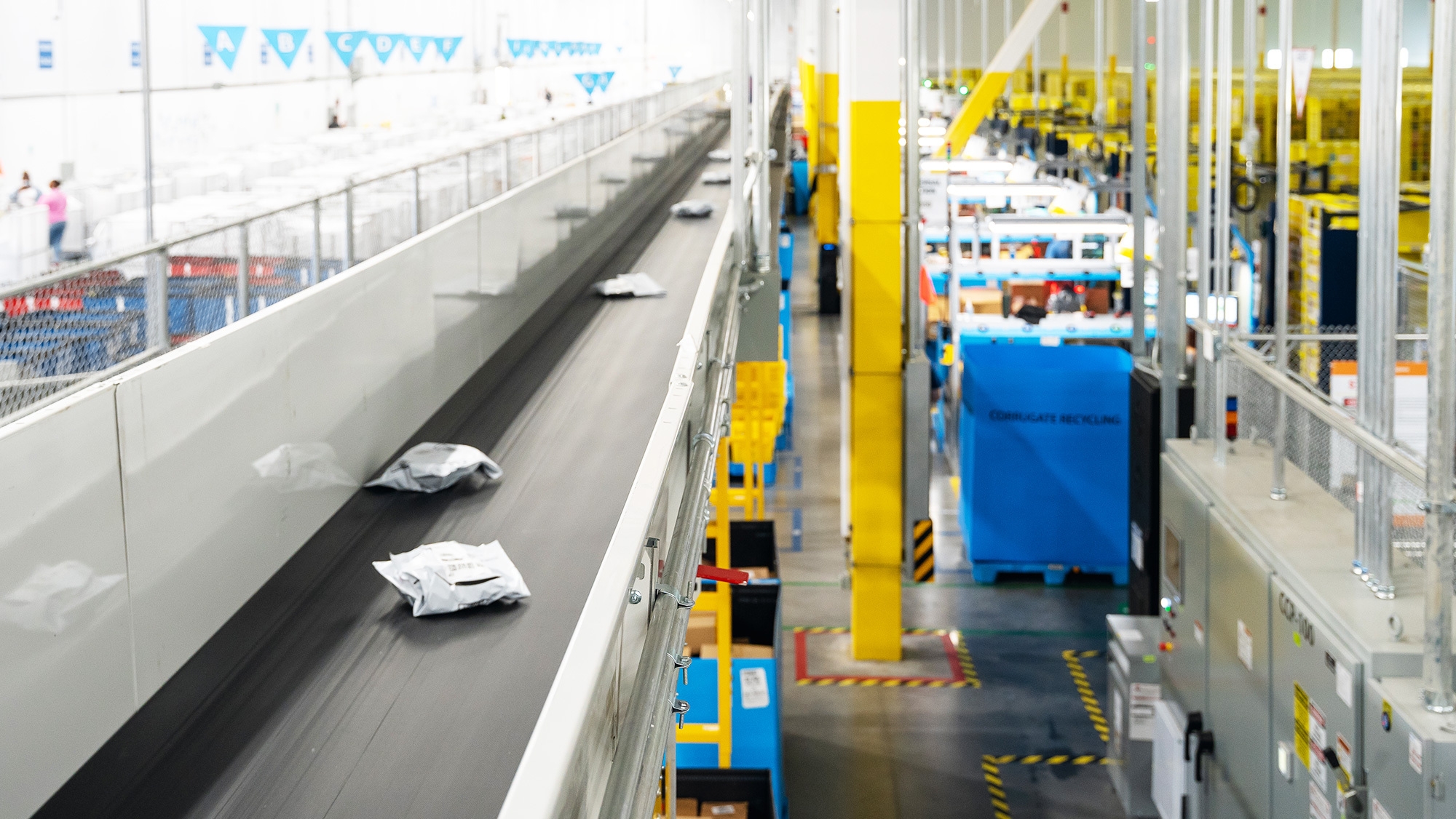 Amazon packages on a conveyor belt in a fulfillment center.