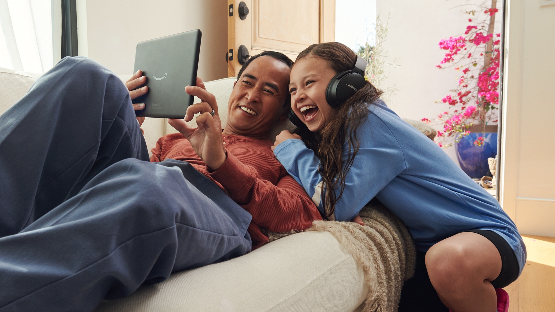 A father and daughter share a laugh while streaming on their Fire tablet. 