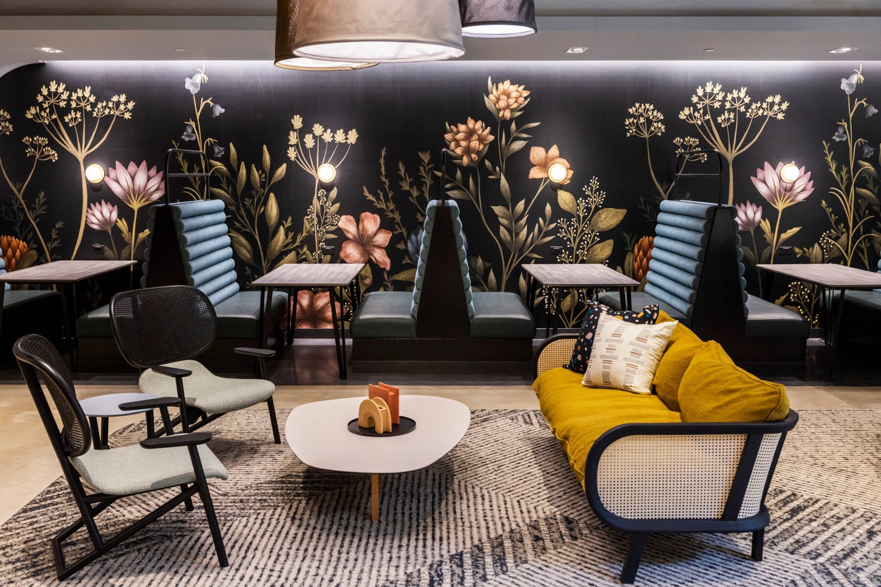 An image of a dining area at Amazon HQ2. There are several seats in jewel tones and floral wallpaper on the walls.