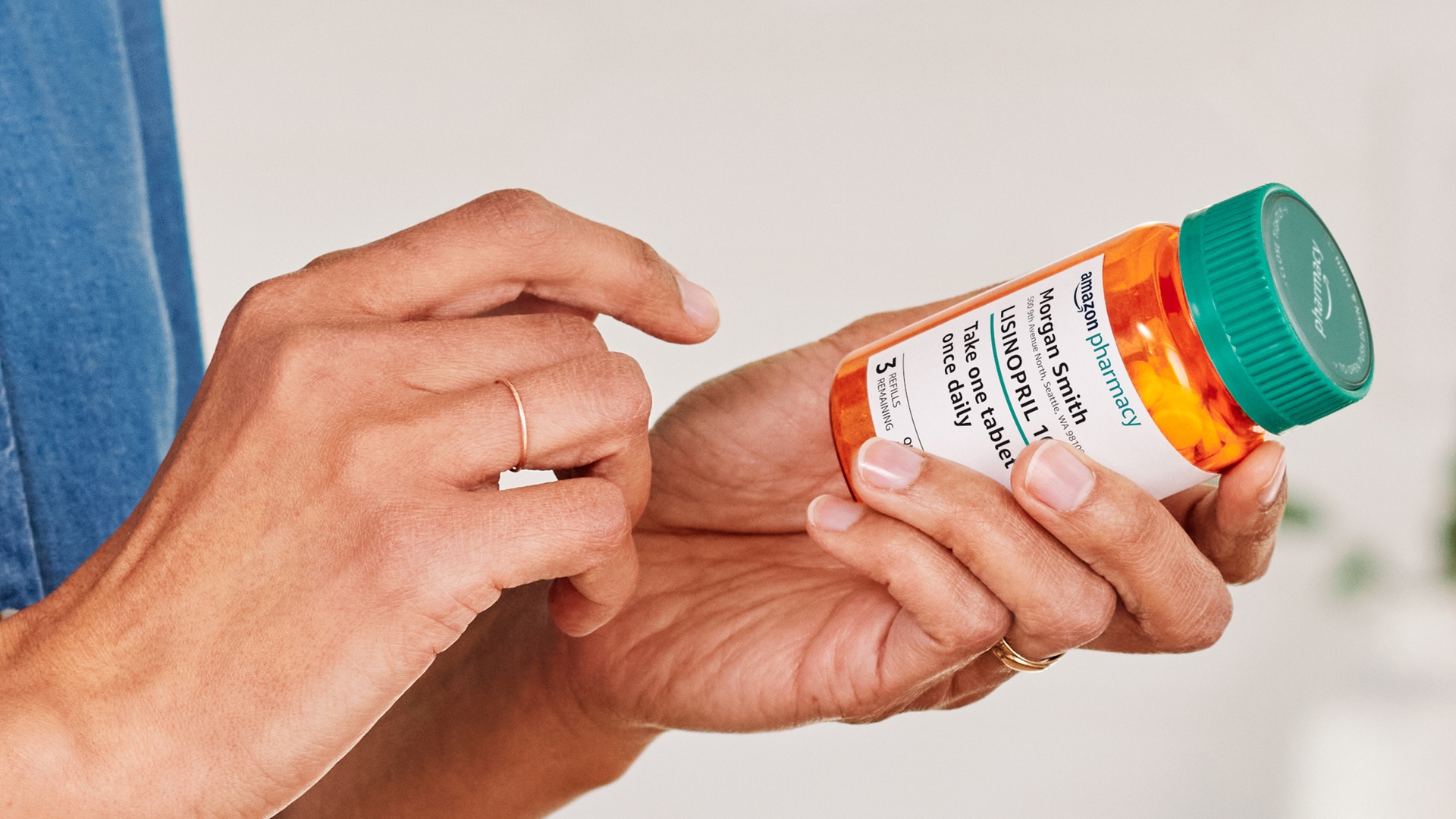 image of pair of hands one is holding a bottle of lisinopril prescribed through amazon pharmacy